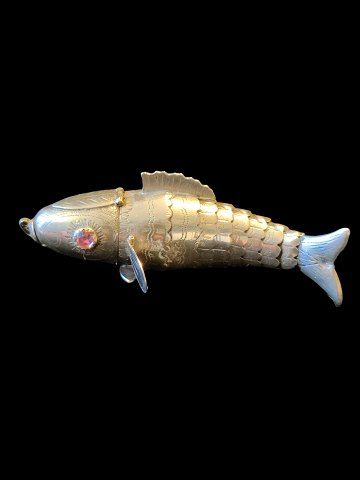 Fiskeformet hovedvandsæg af sølv med bevægelig krop og øjne af glasflusser. 
Oplukkeligt hoved og mund. 1900-tallet.